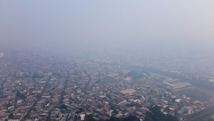 Imagem colorida mostra vista aérea de Manaus encoberta por fumaça